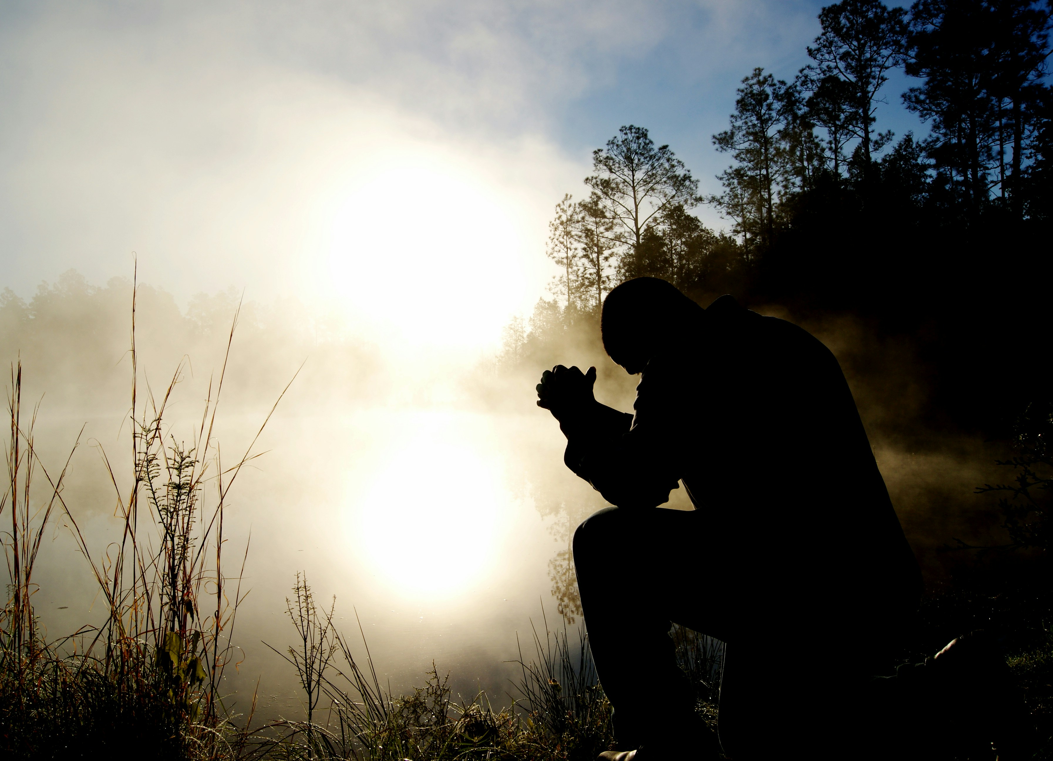 Person in silhouette bowing in prayer at sunrise, representing morning devotion and gratitude in retirement